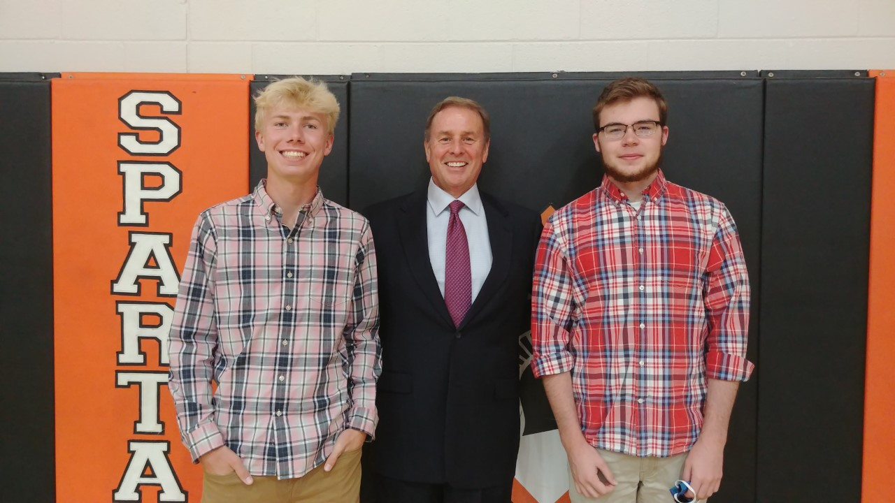 three people in front of an orange and black wall